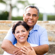older couple smiling in front of brick wall