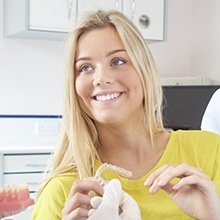 Woman in dental chair holding Invisalign tray