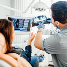 Dentist showing X-rays to a patient in dental chair