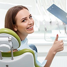 Woman in dental chair giving thumbs up