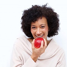 smiling woman biting into red apple 