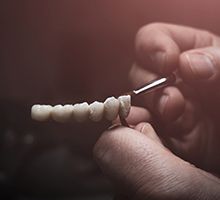 Lab technician painting replacement teeth