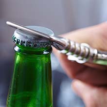 Closeup of patient using bottle opener to prevent dental emergencies in Virginia Beach