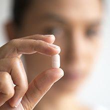 Hand holding a white tablet pill