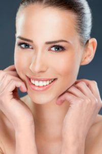 Beautiful woman smiling, close up over a dark background