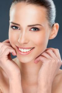 Beautiful woman smiling, close up over a dark  background