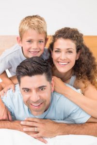 Attractive young family smiling at camera on bed posing