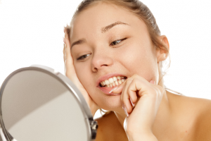 woman looking at teeth in mirror