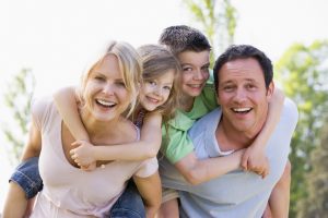 family of four hugging smiling