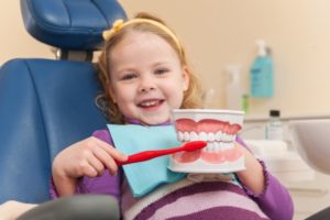 child in dentist's chair pretending to brush teeth mold