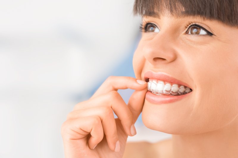 attractive woman inserting Invisalign aligner