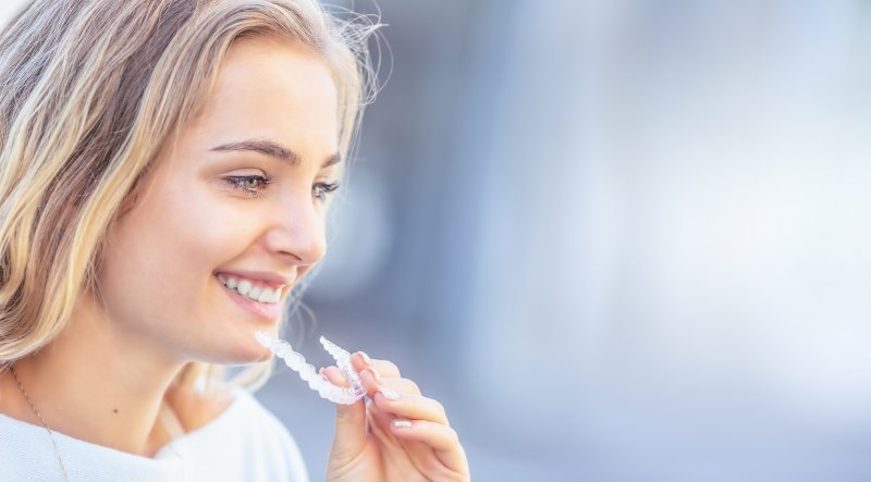 young woman smiling inserting Invisalign in virginia beach 
