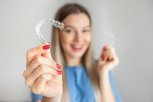 Woman holding clear aligner. 